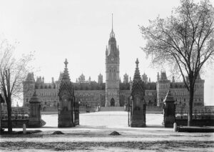 Installée en 1876, la porte de la Reine en fer forgé est l’un des plus anciens éléments caractéristiques de la Colline du Parlement. On la voit ici sur une photo d’archive prise en 1900 par Alexander W. Galbraith devant l’édifice du Parlement original, qui a été détruit dans l’incendie de 1916. (Crédit photo : Archives de la ville de Toronto, Fonds 1568, article 208)